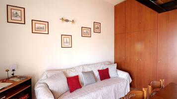 Una habitación con sofá, armario de madera y cuadros en la pared.