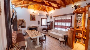 Una sala de estar acogedora con chimenea, vigas de madera en el techo, un sofá, una mesa y una estantería.