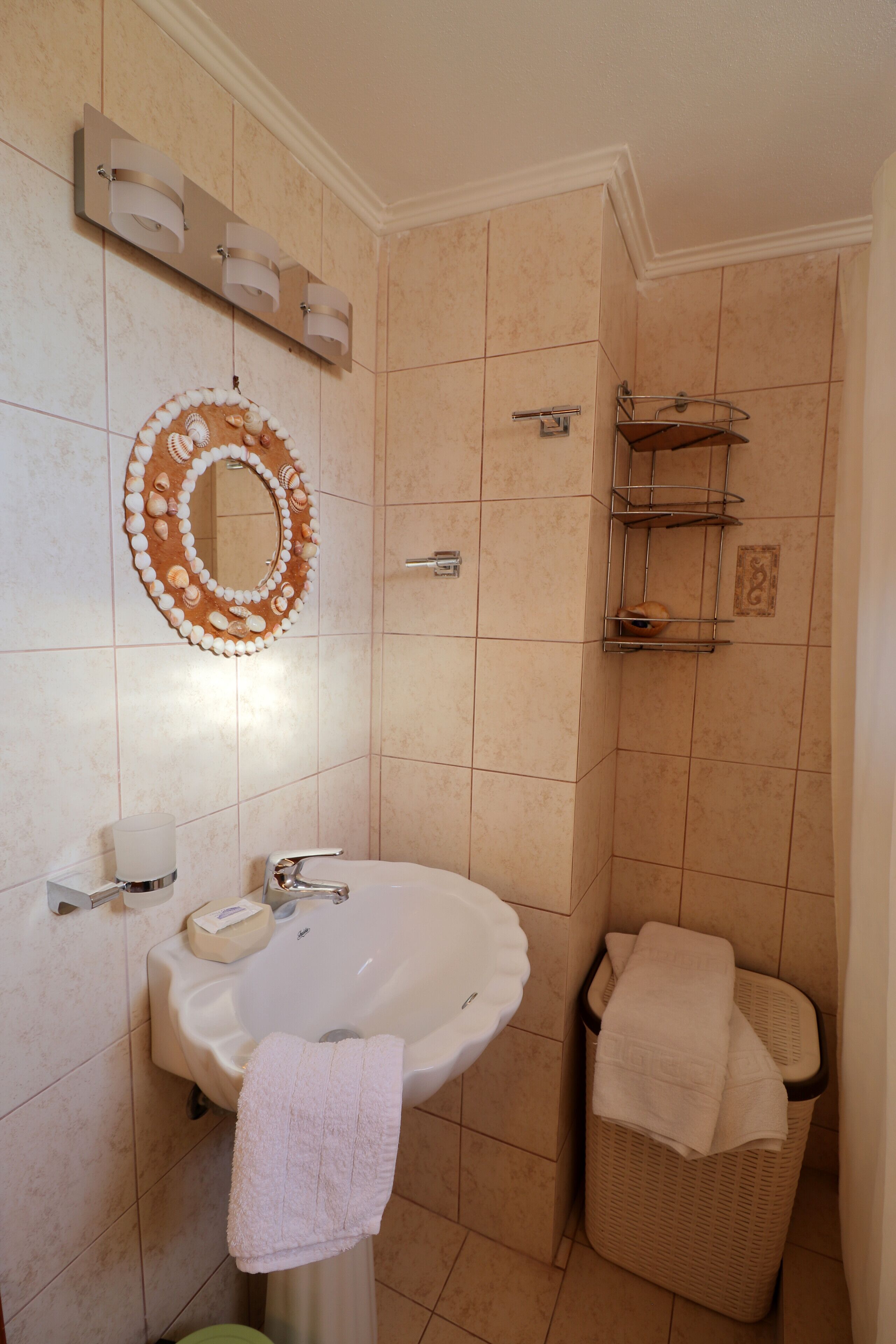 Un baño con lavamanos, espejo, toallero y un cubo de basura.