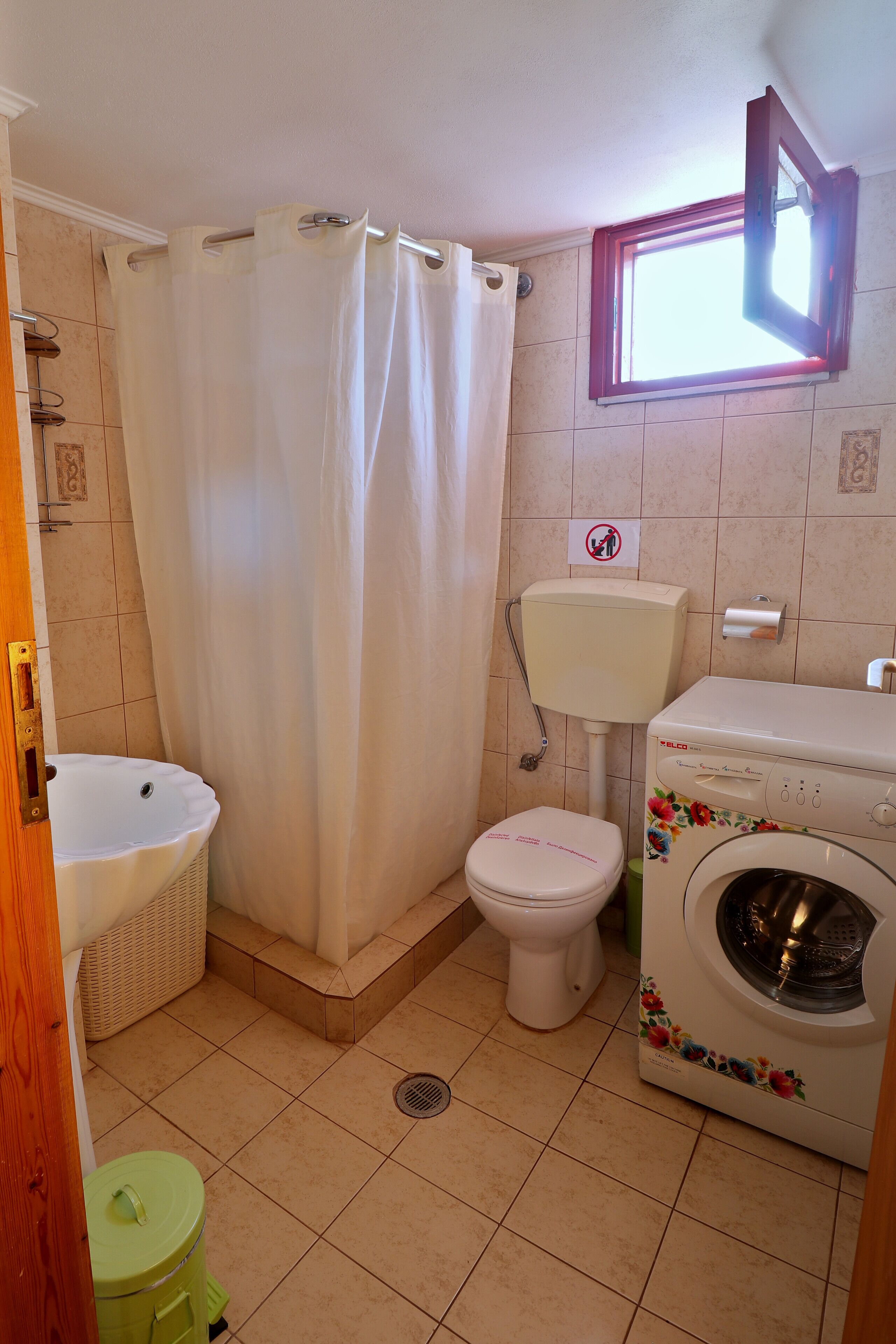 Un bagno con tenda della doccia, servizi igienici, lavandino e lavatrice.