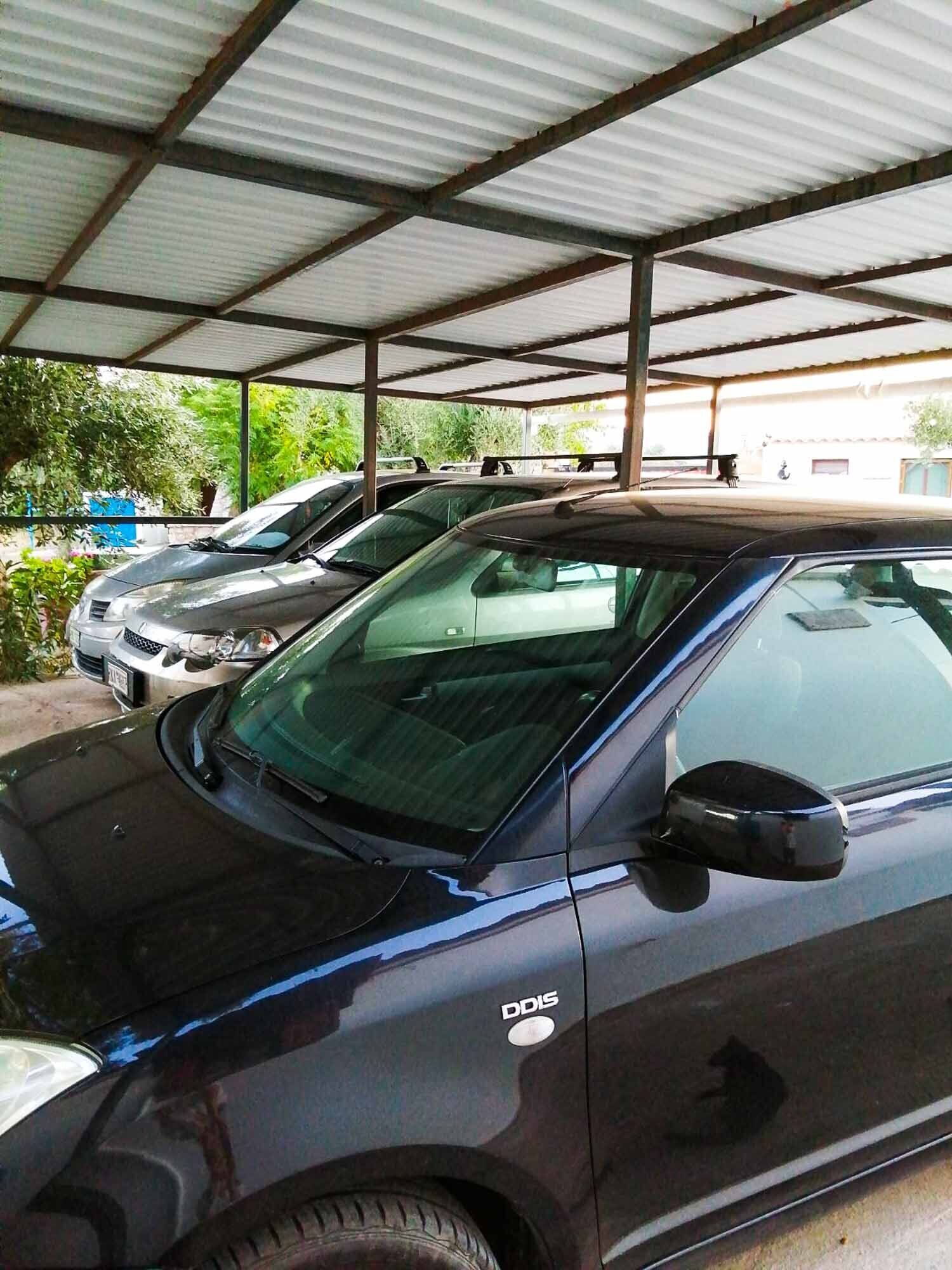 Un área de estacionamiento techada con varios coches, incluyendo una berlina negra con un logotipo visible en la puerta.