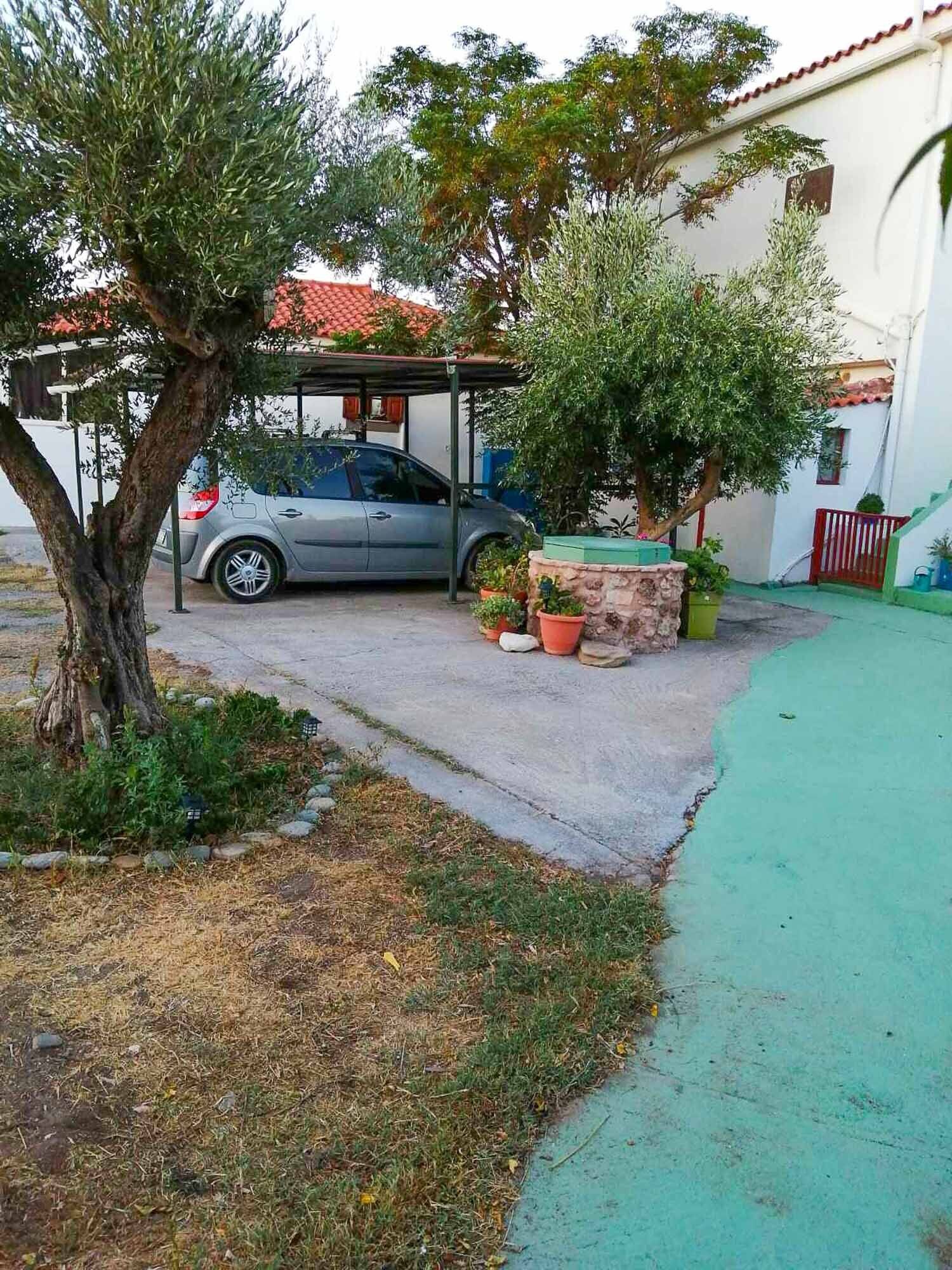 Auto on pysäköity katoksen alle, ja taustalla näkyy rakennus.