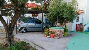 Auto on pysäköity katoksen alle, ja taustalla näkyy rakennus.