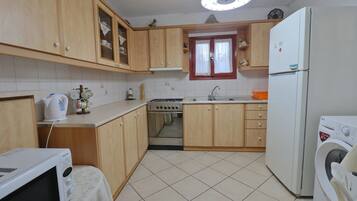 A kitchen with wooden cabinets, a microwave, a stove, a sink, and a washing machine.