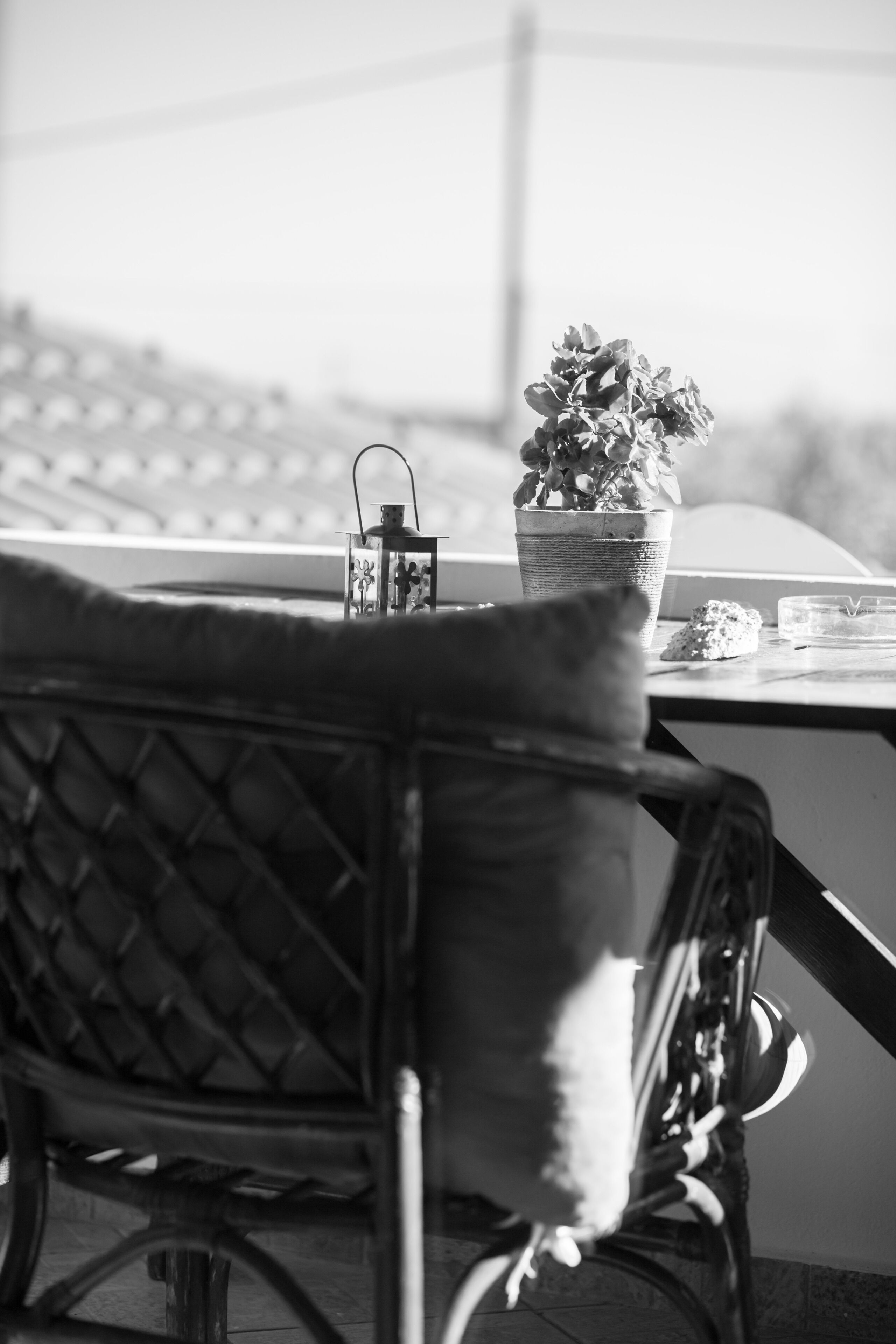 Ein Korbstuhl mit Kissen, ein Blumentopf, ein Glas Wasser und eine kleine Schale auf einem Tisch.
