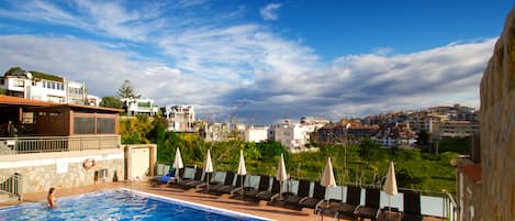 Una piscina al aire libre, camas de piscina gratis, sombrillas