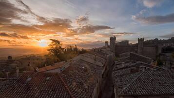 A historic town with medieval architecture, including towers and a castle, during sunset.