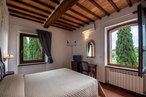 Quarto com cama, escrivaninha, cadeira, janela com cortinas, espelho e radiador.