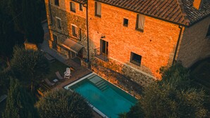 Vue aérienne d’un bâtiment en pierre à deux étages, avec une piscine au premier plan.