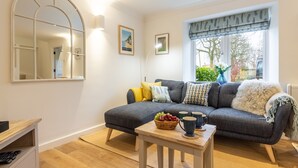A cozy living room with a grey sofa, wooden coffee table, and a large mirror. - Cherry Tree Cottage, Great Bircham, Norfolk (Great Bircham)