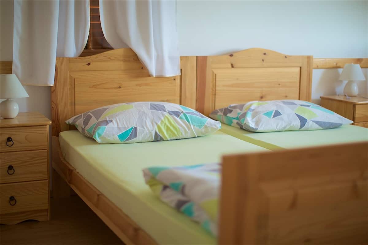 A double bed with a wooden headboard, two bedside tables with lamps, and a nightstand with drawers.