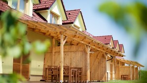 Un bâtiment en bois doté d’un patio couvert, de nombreuses fenêtres et d’un toit recouvert de tuiles rouges.