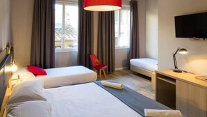 Une chambre d’hôtel avec deux lits, un bureau, une chaise et un téléviseur.