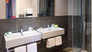Une salle de bain moderne avec deux lavabos, une douche en verre et un miroir.