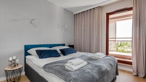 Een moderne slaapkamer met een bed, nachtkastje en raam met gordijnen.