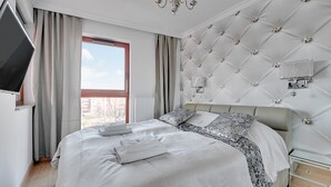 Een hotelkamer met een groot bed, een flatscreen televisie aan de wand en een raam met gordijnen.