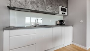Een moderne keuken met een ingebouwde magnetron, een roestvrijstalen spoelbak en een koffiezetapparaat op het aanrecht.