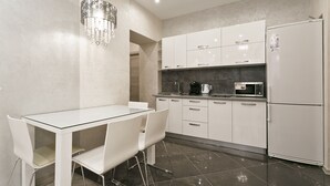 Una cocina moderna con armarios blancos, una mesa de vidrio y una araña.