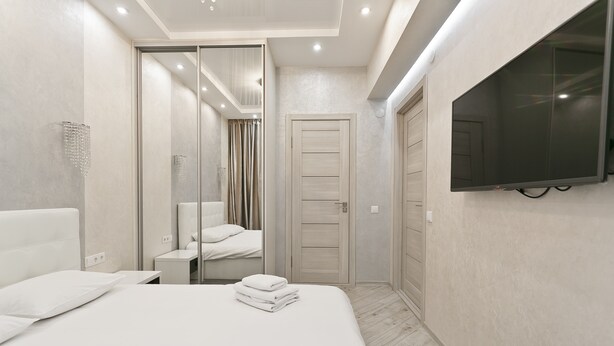 Una habitación de hotel moderna con una cama grande, un televisor montado en la pared y un vestidor.