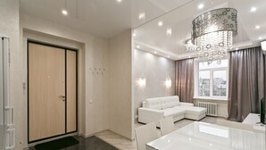 Una sala de estar moderna con un sofá blanco, una mesa de comedor de vidrio y una araña.