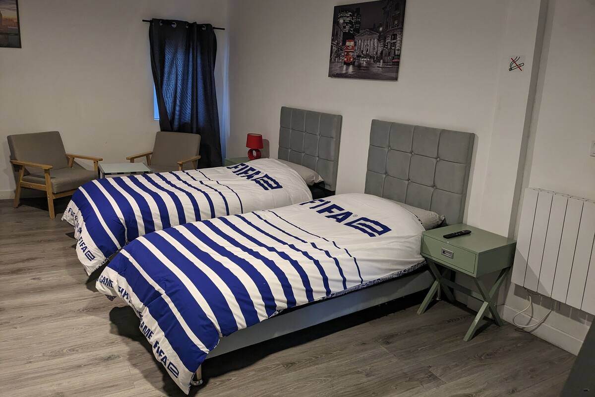 Un lit double avec une literie à rayures, une table de chevet avec une lampe, une chaise et un tableau au mur.