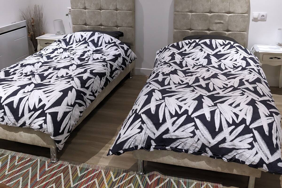 Une chambre à coucher avec deux lits, chacun doté d’une tête de lit capitonnée, d’une table de chevet et d’une lampe.