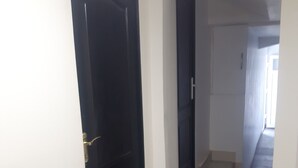 A hallway with a black door and a staircase leading to another room. - Guesthouse near Charles De Gaulle Airport (Thieux)