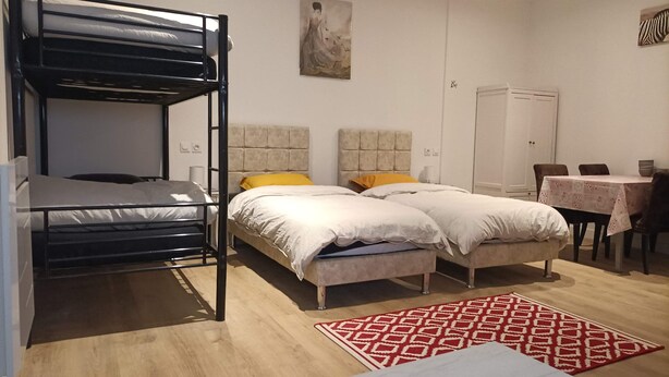 A room with a bunk bed, a double bed, a desk with a chair, and a wardrobe. - Guesthouse near Charles De Gaulle Airport (Thieux)