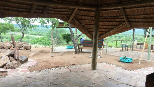 A covered outdoor area with stone flooring, wooden benches, and a thatched roof structure. - Paje River Camp (Paje)