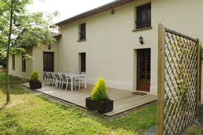 A house with a deck, outdoor seating, and a wooden fence.