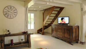 A living room with a wooden staircase, a television, a wooden cabinet, and a large wall clock. - Large comfortable cottage 10 people (Rosnay-l'Hôpital)