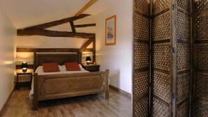 A bedroom with a wooden bed, a nightstand, a lamp, and a decorative partition. - Large comfortable cottage 10 people (Rosnay-l'Hôpital)
