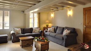A living room with two grey sofas, a wooden coffee table with flowers, a lamp, and a wooden door. - Large comfortable cottage 10 people (Rosnay-l'Hôpital)