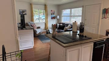 Een compacte woonruimte met een kitchenette, een eethoek en een zithoek met een bank.