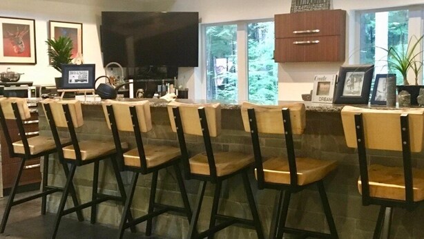 Un espace bar avec des tabourets hauts et un téléviseur.