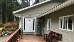 Une terrasse en bois avec des chaises, une porte blanche et une fenêtre.