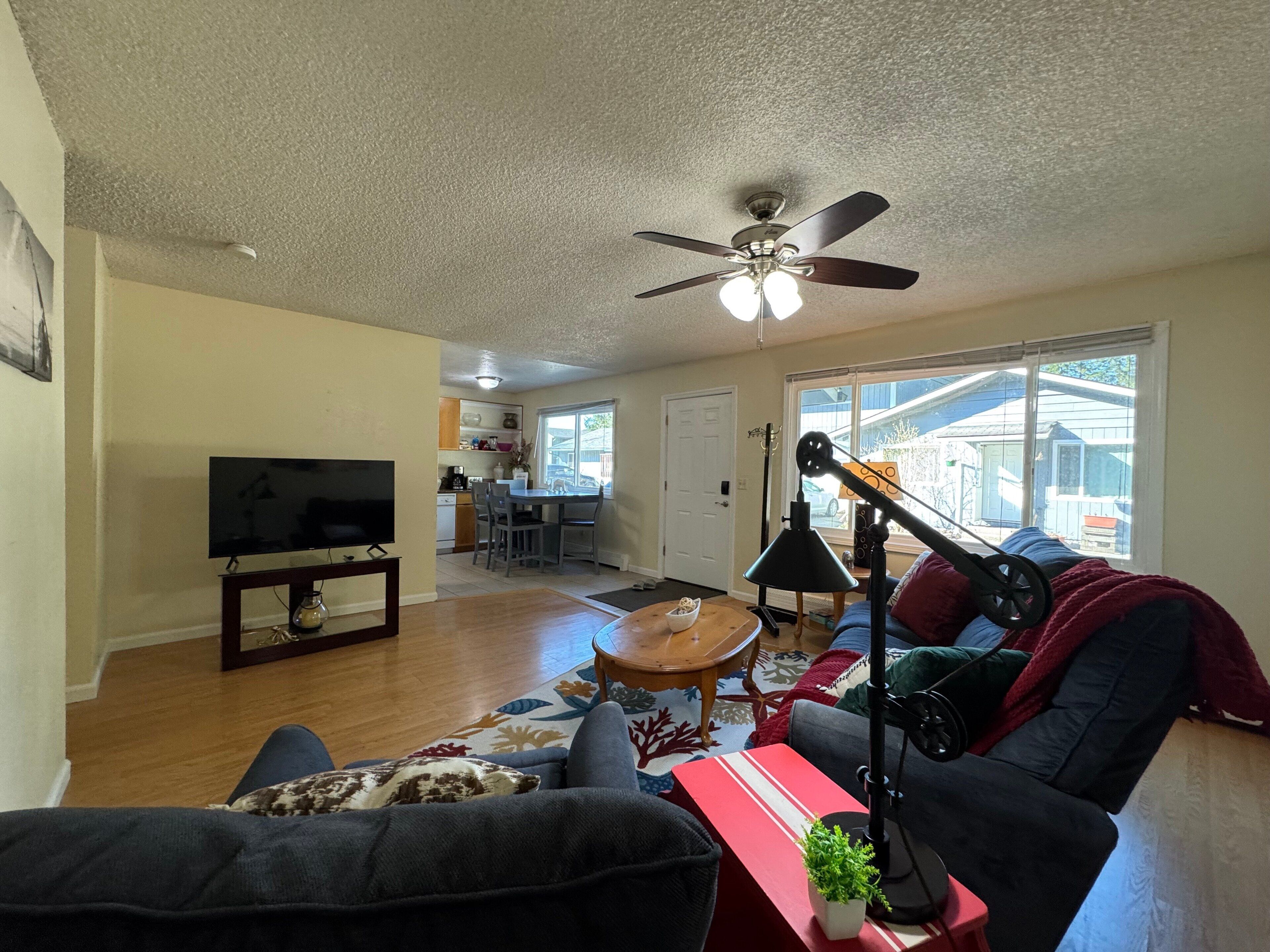 Ein Wohnzimmer mit Fernseher, Sofa, Couchtisch und Deckenventilator.