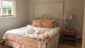 Une chambre à coucher avec un lit à baldaquin, une table de chevet avec une lampe et une fenêtre avec des stores.