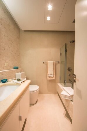 A modern bathroom with a bathtub, toilet, and shower.