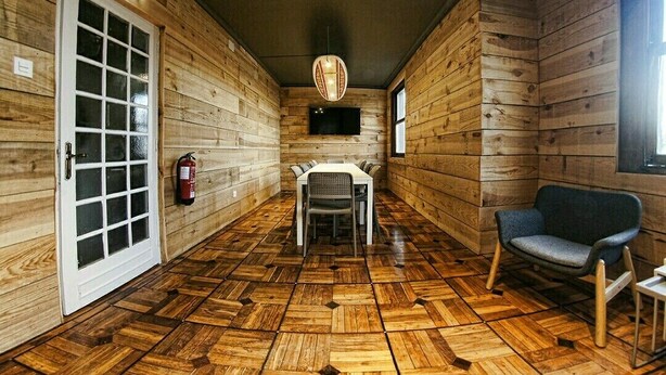 Un interior de madera con una mesa de comedor, sillas, un extintor, un televisor y un sofá.