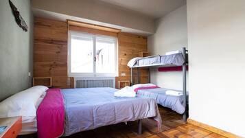 Un dormitorio con dos camas, paredes de madera, una ventana y un radiador.