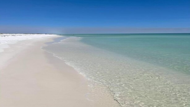 Ein Strand mit klarem türkisblauem Wasser und einem Sandstrand.