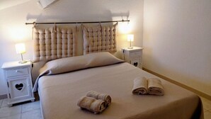 Ein Hotelzimmer mit einem großen Bett, zwei Nachttischen mit Lampen und einem mit Wirbeln verzierten Kopfteil.