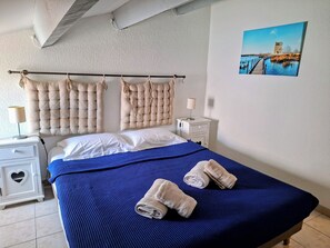 A hotel room with a bed, a nightstand, a lamp, a picture on the wall, and a window.