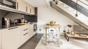 Une cuisine moderne dotée d’un four encastré, d’un plan de travail en bois et d’un coin bar avec des tabourets.