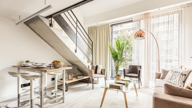 Un salon moderne avec un escalier, un coin repas et un canapé.