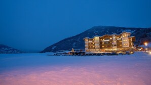 Un hôtel à plusieurs étages, doté d’un restaurant et d’un café, entouré de montagnes enneigées.