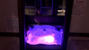Un bain à remous avec un éclairage violet, entouré de fenêtres et agrémenté d’une enseigne.