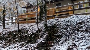 Une cabane en bois dotée d’un balcon, entourée d’arbres et d’un paysage couverts de neige.