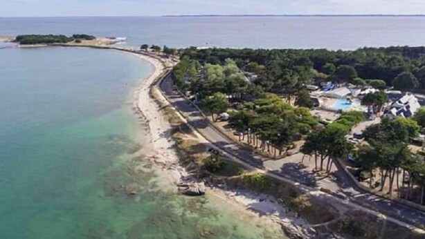 An aerial view of a coastal resort with a sandy beach, a pool, and a row of villas. - Pluvier argenté (Quiberon)